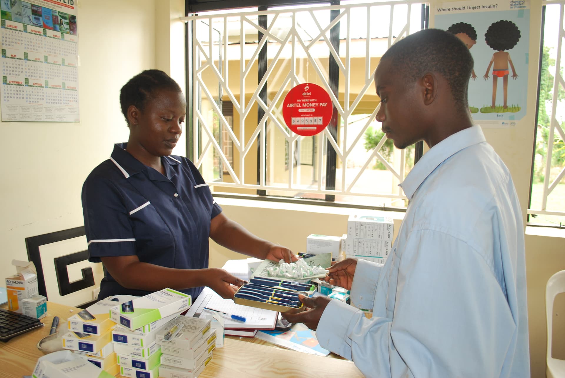 A BrightLife nurse dispenses insulin pens and testing supplies at the clinic counter