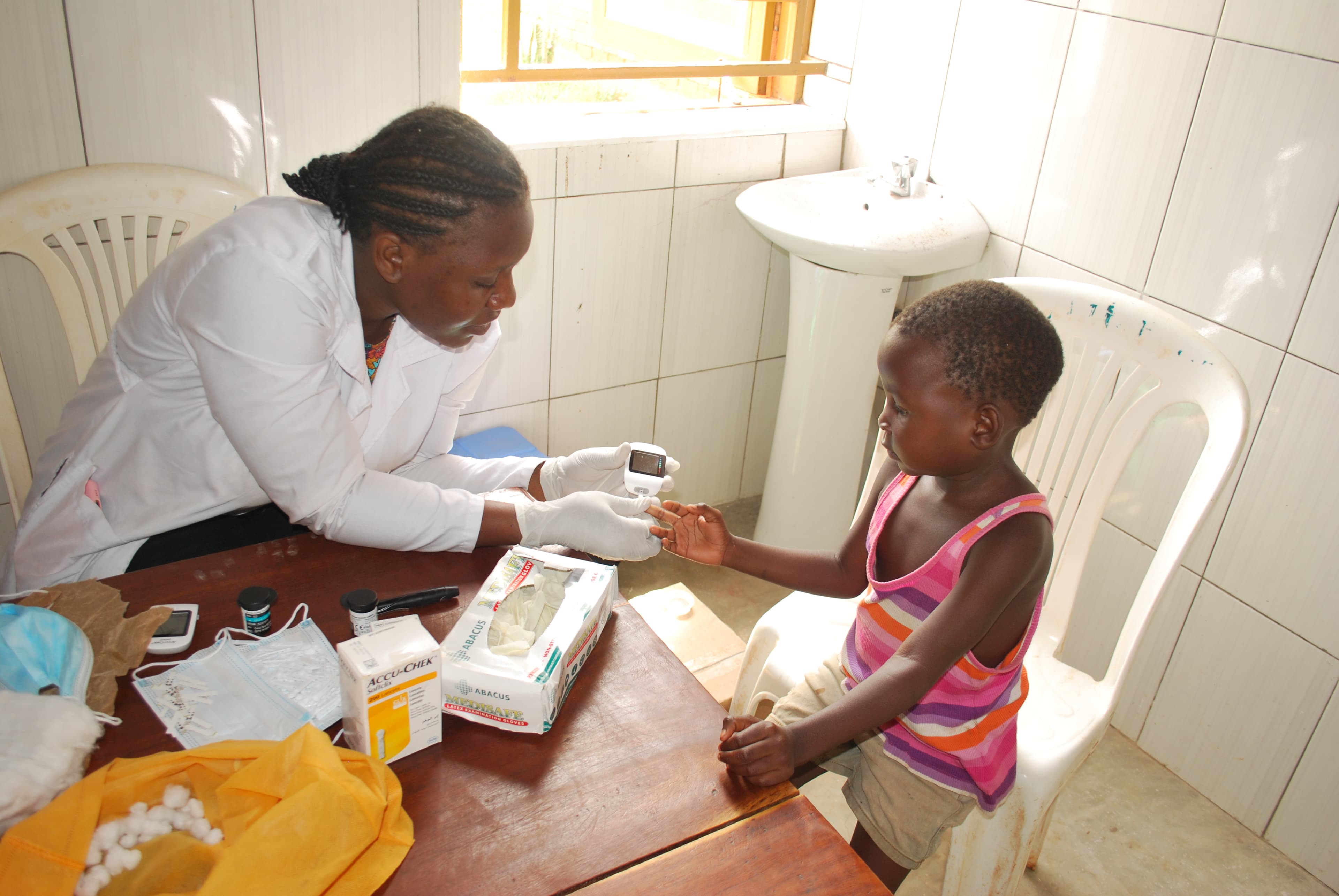 A clinical officer takes a finger-prick blood-glucose reading from a child at the Bright Life Medical Centre.